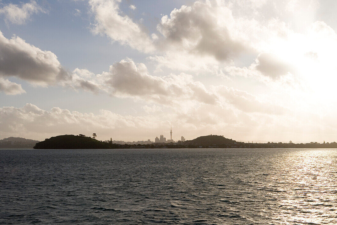 Sonnenuntergang hinter Küste von Takapuna mit Skyline von Auckland, Blick von MS Bremen im Hauraki Gulf, nahe Auckland, Nordinsel, Neuseeland