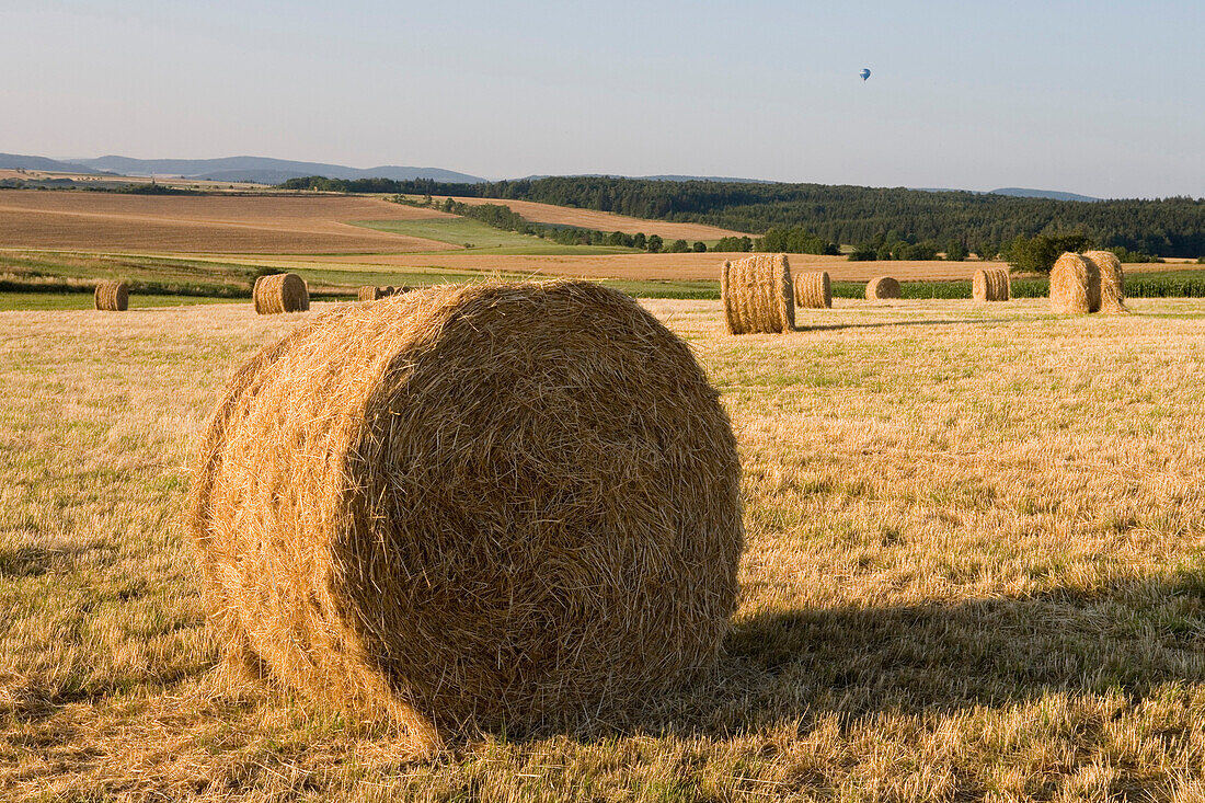 Giant bales of straw in a wheat field, Near Mellrichstadt, Rhoen, Bavaria, Germany