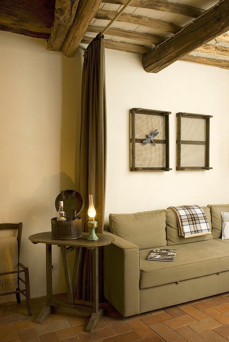 Old wooden side table with kerosene lamp next to a bright green upholstered sofa