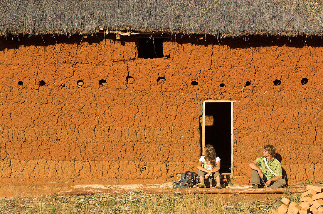 Two hikers having a rest at a typical hut, Madagascar, Africa