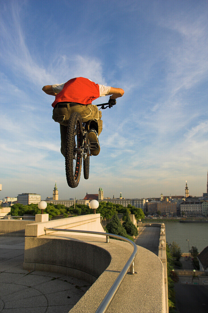 Junger Mann auf einem Trialbike springt über eine Mauer, Linz, Oberösterreich, Österreich