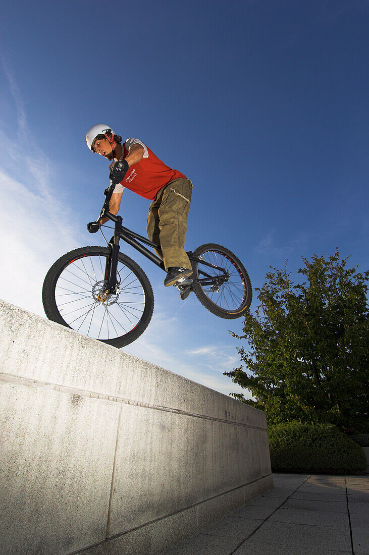 Young man on a trial bike hopping on a wall, Linz, Upper Austria, Austria