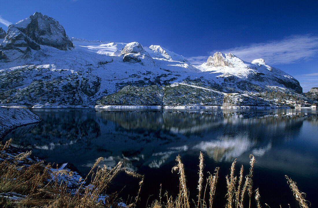 lake Fedajasee with snow-covered range of Marmolada and reflections, Veneto, Italy