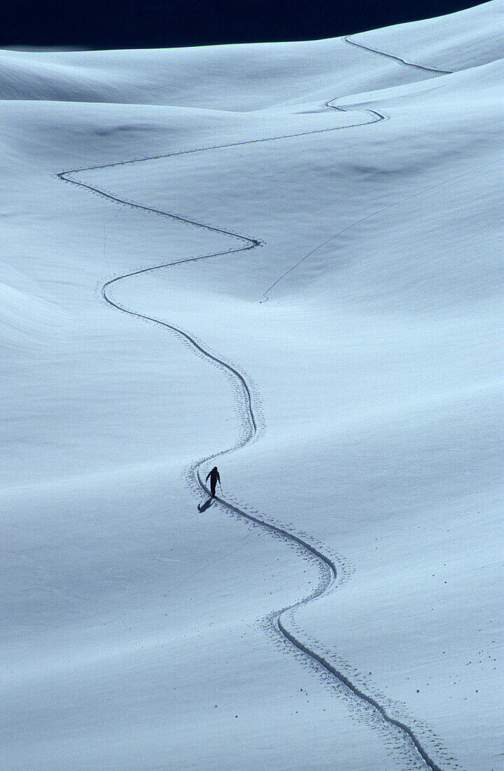 Backcountry skier in track in snow, Piz Laschadurella, Grisons, Switzerland