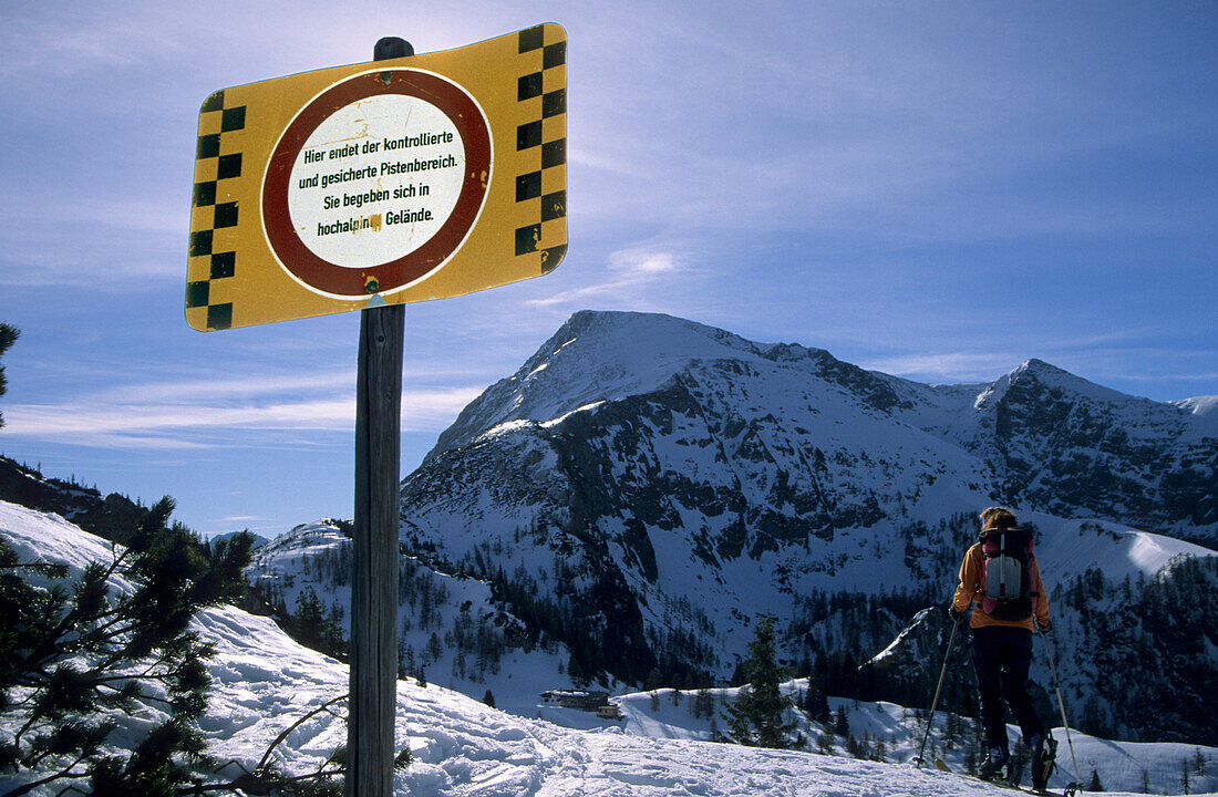 Warntafel Ende des kontrollierten Pistenbereichs am Jenner, im Hintergrund Skitourengeher und Schneibstein, Berchtesgadener Alpen, Oberbayern, Bayern, Deutschland