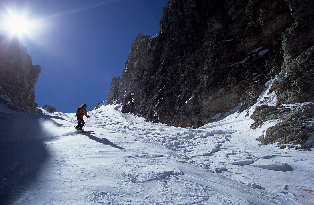 Person skiing down valley Val Mezdi, Sella range, South Tyrol, Alta Badia, Italy