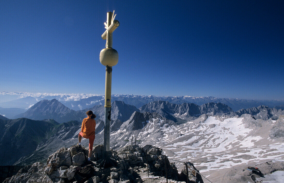 Woman next to summit cross on summit of Zugspitze, Wetterstein range, Upper Bavaria, Bavaria, Germany