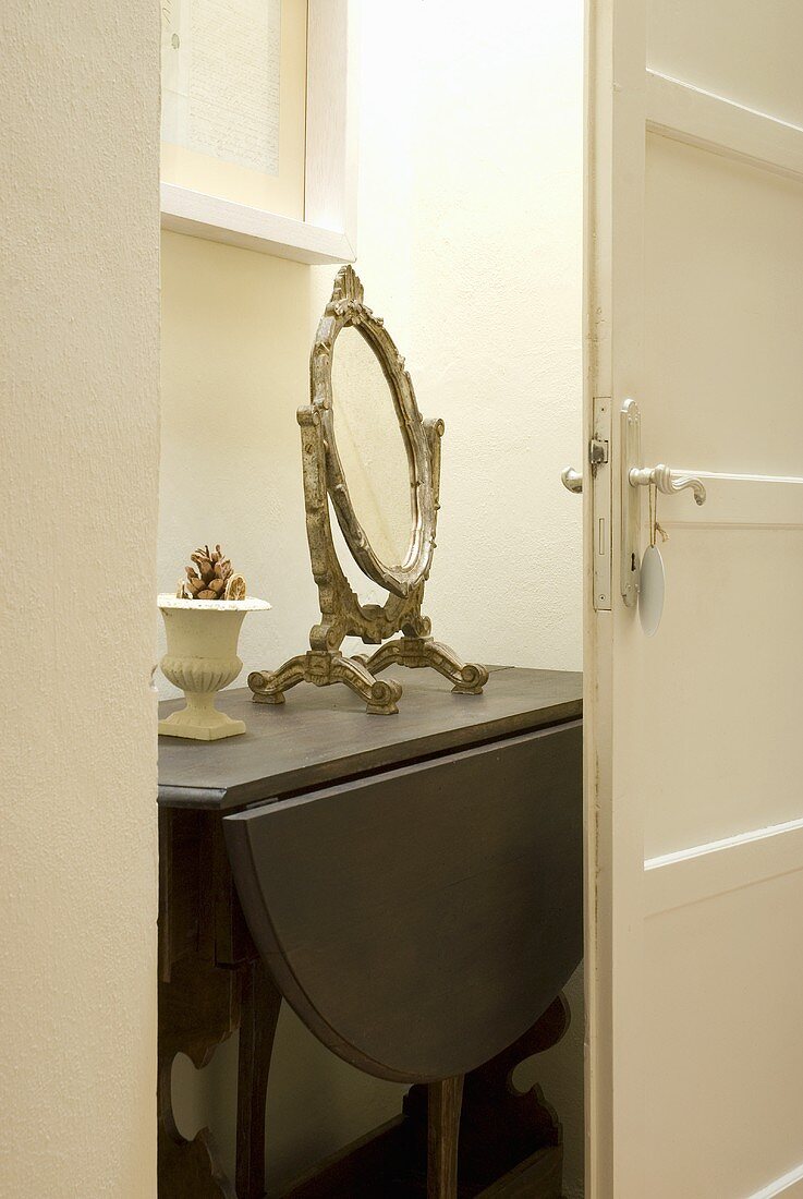 Antique makeup mirror on a folding wall table in a niche