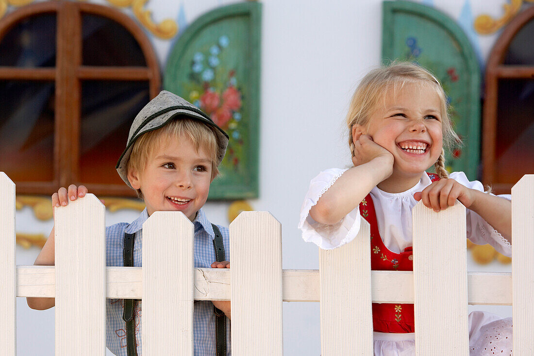 Two children (3-5 years) standing behind a fence