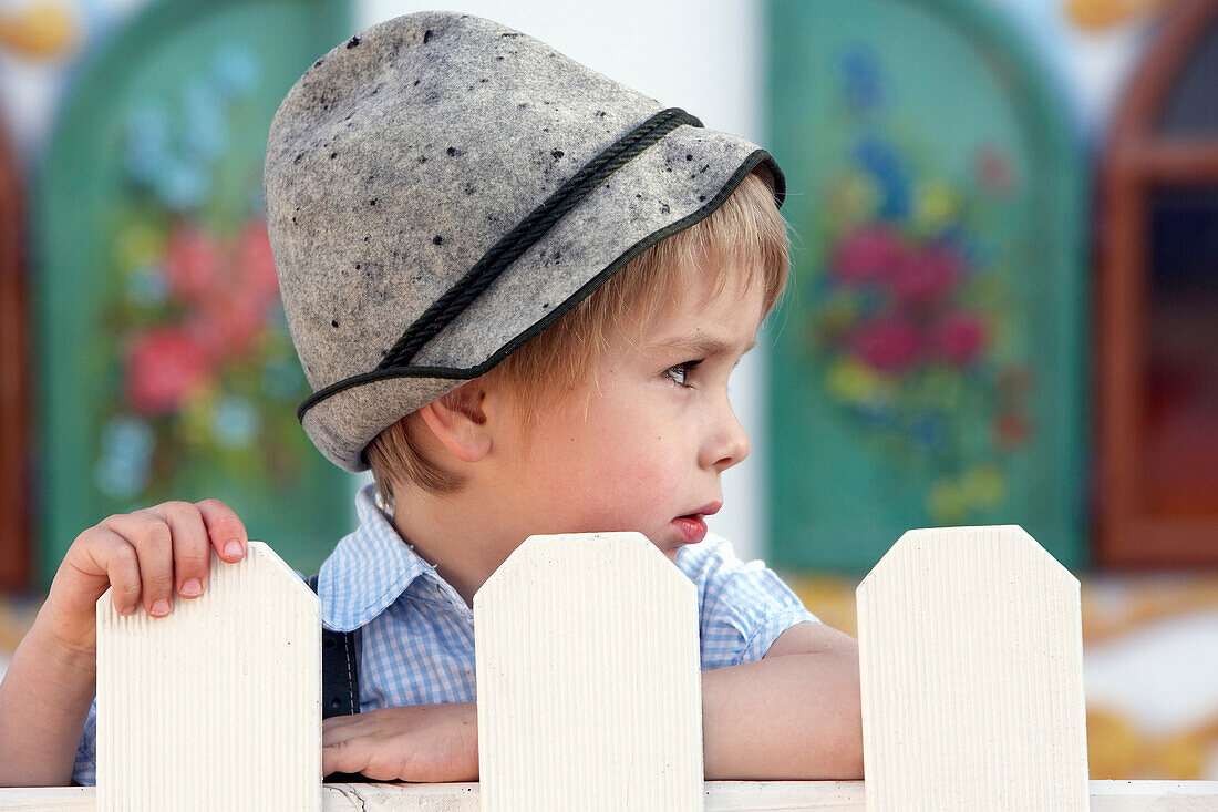 Boy (3-4 years) standing behind a fence