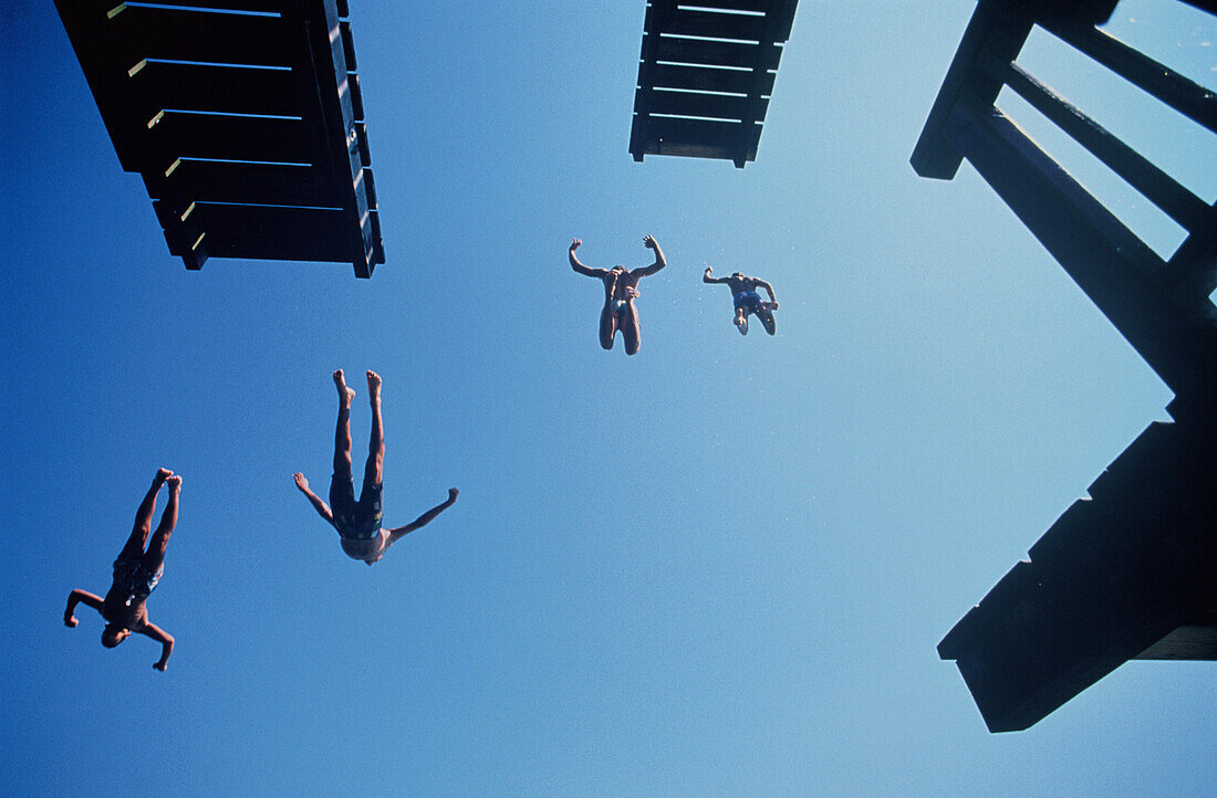 Four people juming from diving platform into water, Lake Ammer, Bavaria, Germany