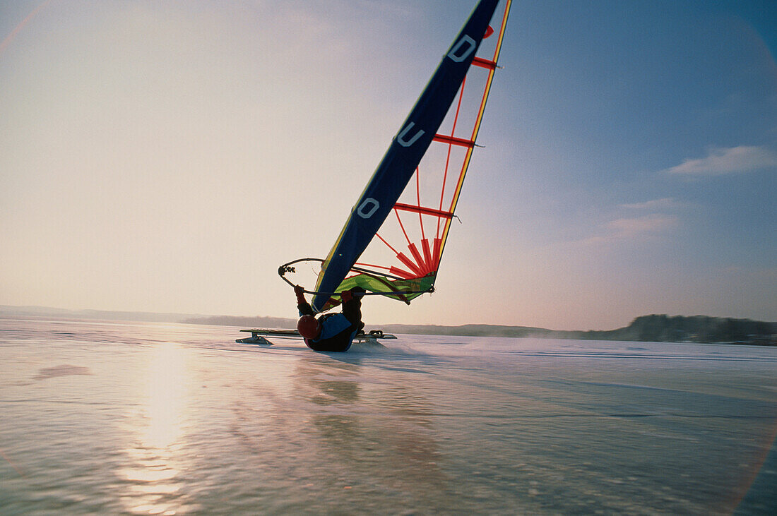 Ice yachting on lake Wörthsee at sunset, Bavaria, Germany