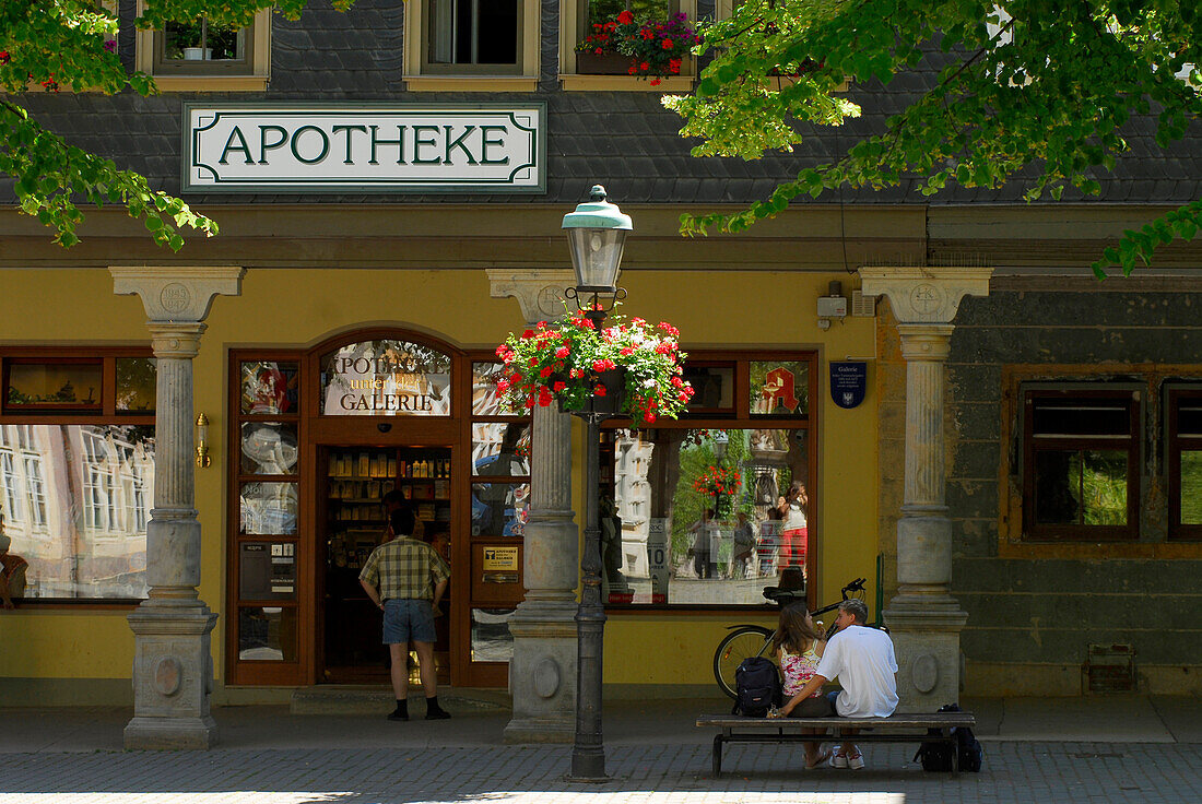 A couple sitting outside the pharmacy at the market square, Arnstadt, Thuringia, Germany