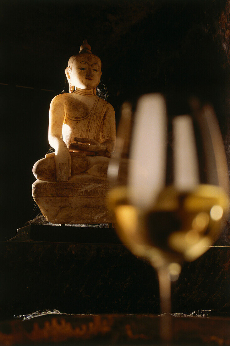 Buddha statue and a white wine glass
