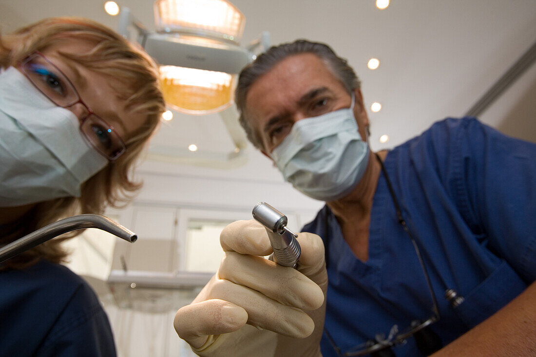 Zahnbehandlung, Zahnbehandlung beim Zahnarzt, Zahnarzt und Helferin beugen sich über den Patienten. Praxis Dr. Vesic, Hannover