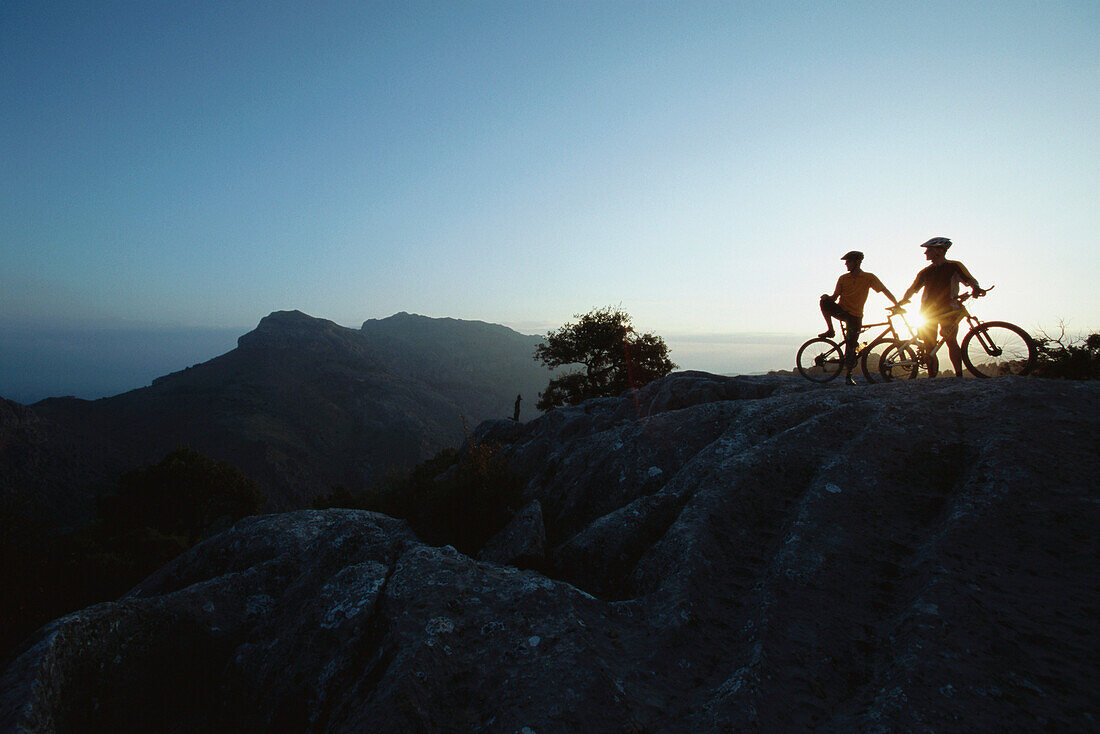 Two mountain bikers in sunset, Torret de Pareis, Mallorca, Balearic Islands, Spain