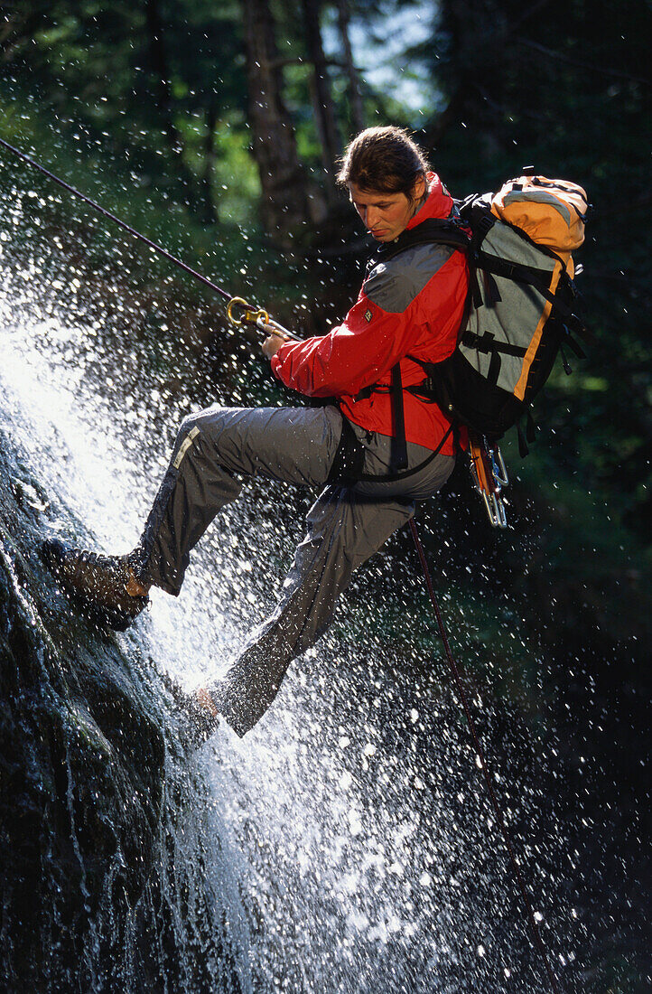 Man climbing, descending down a waterfall. Lake Sylvenstein, Upper Bavaria, Bavaria, Germany