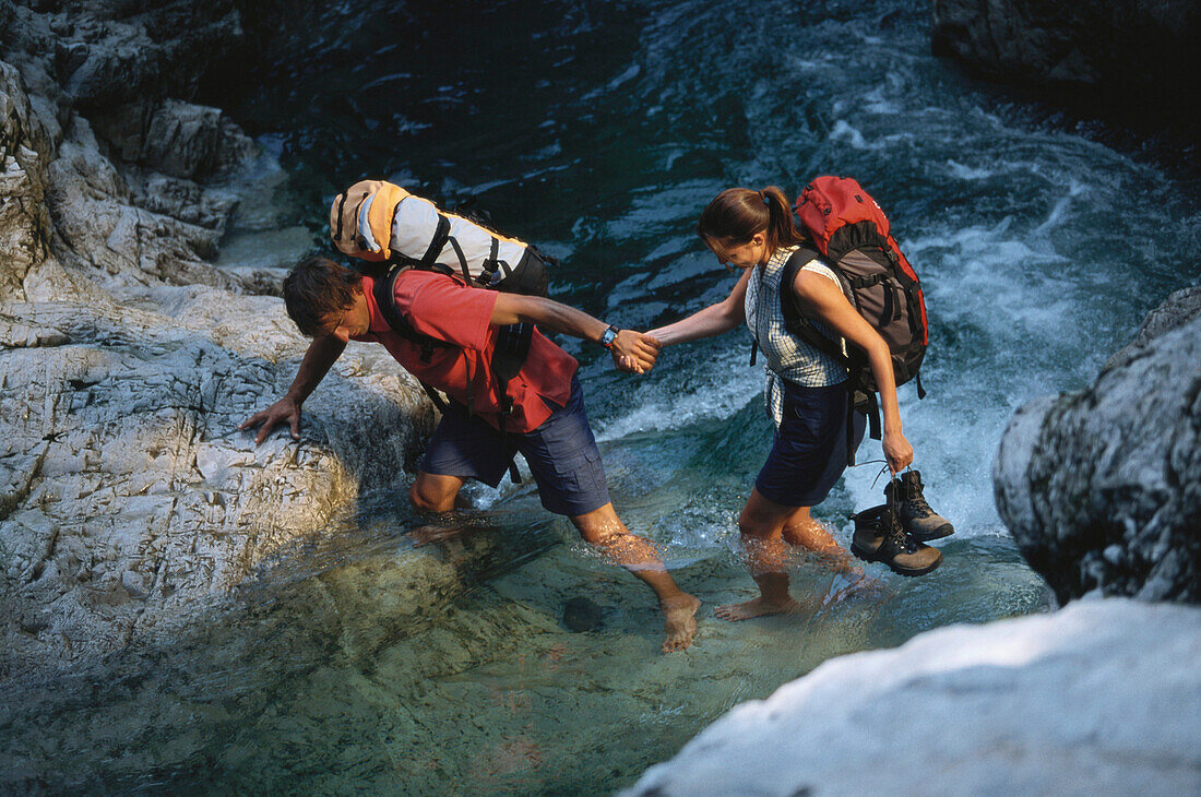 Couple crossing waterfall at Sylvenstein, Bavaria, Germany