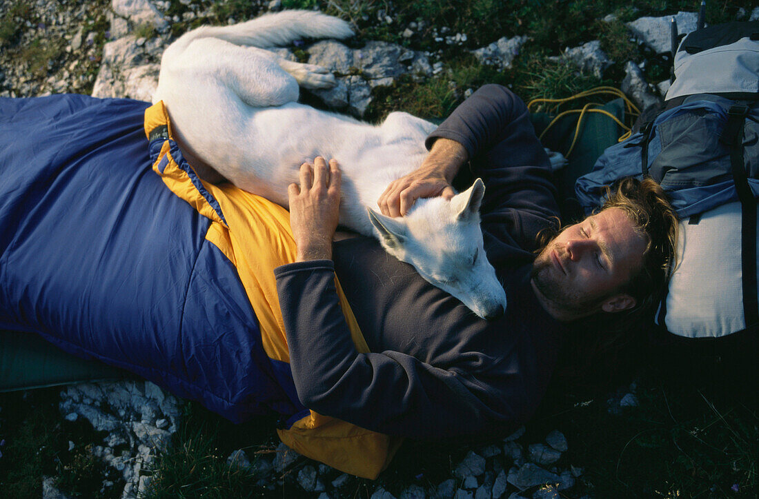 Man with dog sleeping in a sleeping bag, mount Alpspitz, Garmisch-Partenkirchen, Bavaria, Germany