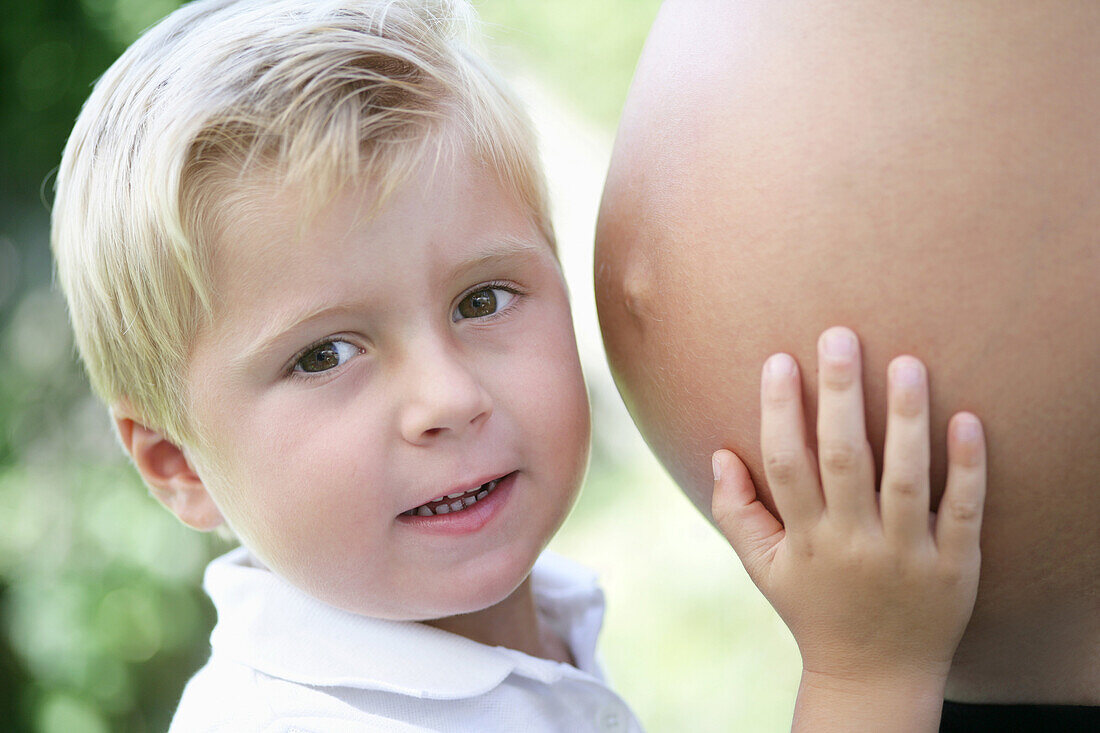 Boy (4-5 years) touching pregnant woman's belly, Styria, Austria