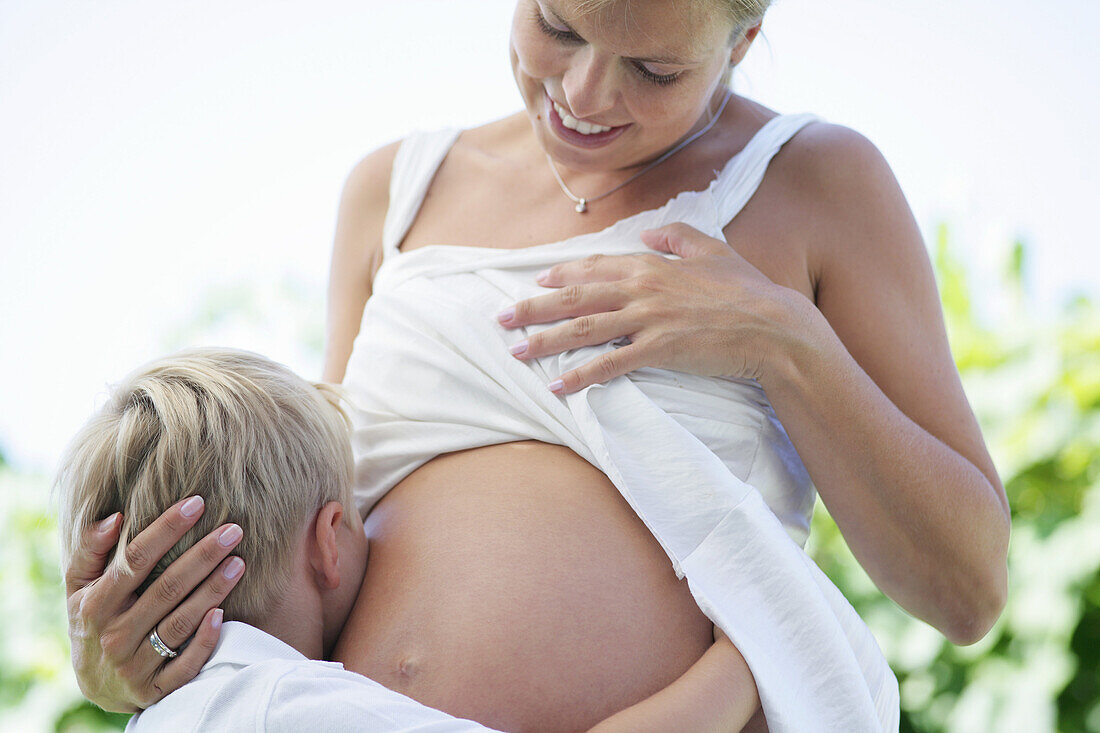 Boy (4-5 years) embracing pregnant mother's belly, Styria, Austria