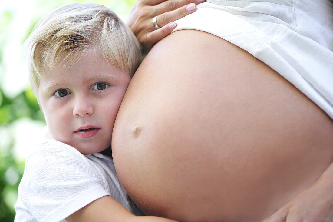 Boy (4-5 years) embracing pregnant mother's belly, Styria, Austria