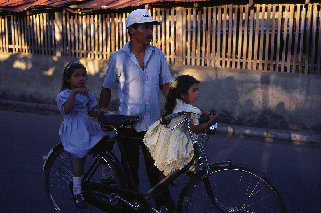 Man pushing two children on a bike, Granada, Nicaragua, Central America