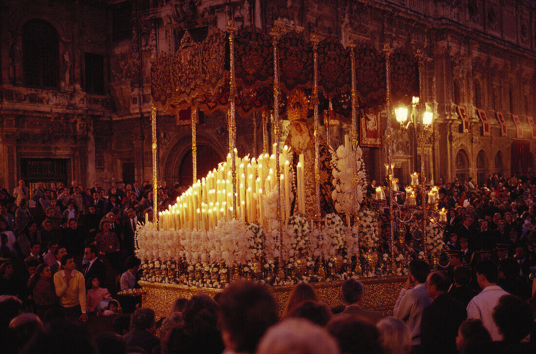 Menschen tragen am Abend eine tonnenschwere, mit Kerzen geschmückte Marienstatue zur Kathedrale, Plaza San Francisco, Sevilla, Andalusien. Spanien