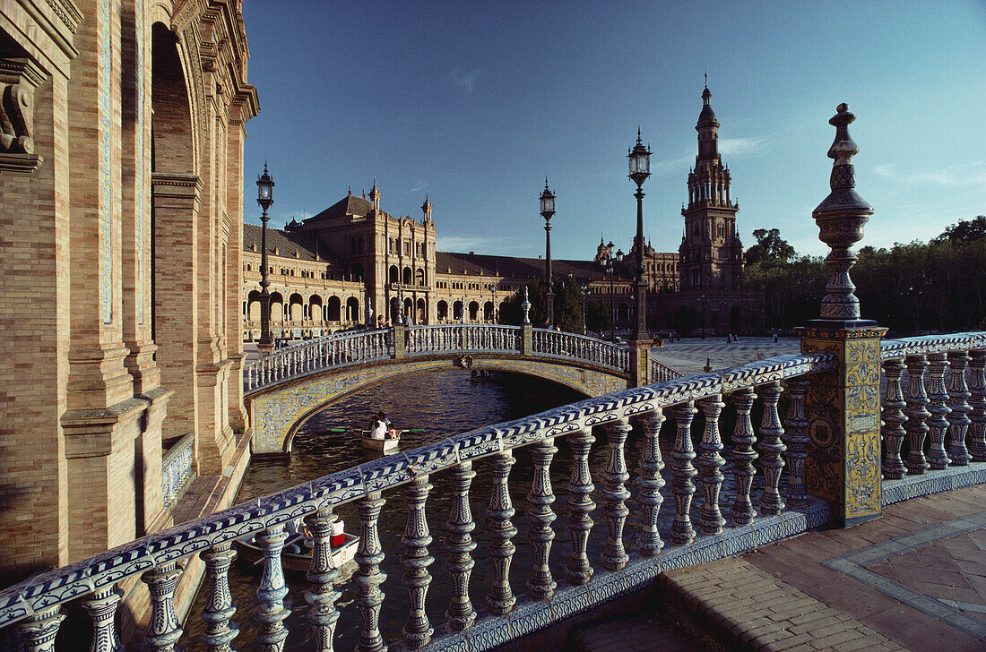 Zierliche Brücken mit Geländern aus blau glasierter Keramik über Kanal mit Ruderbooten am Palacio Central, Sevilla, Andalusien. Spanien