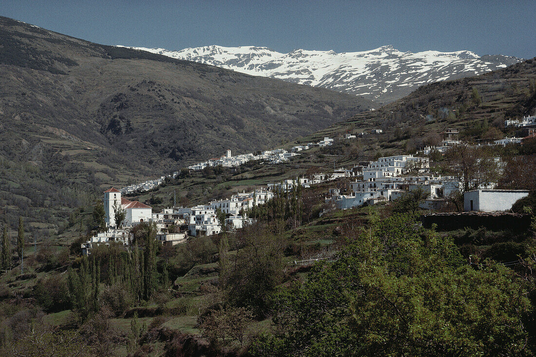 Zwei weiße Dörfer Bubión und Capileira im Hochtal der Alpujarras unter verschneiten Gipfeln der Sierra Nevada, Provinz Granada, Andalusien. Spanien