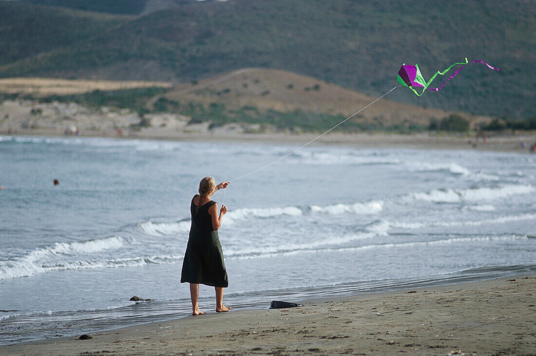 Mädchen lässt einen Drachen steigen am Strand, Playa de los Genoveses, Parque Natural Cabo de Gata, Andalusien, Spanien