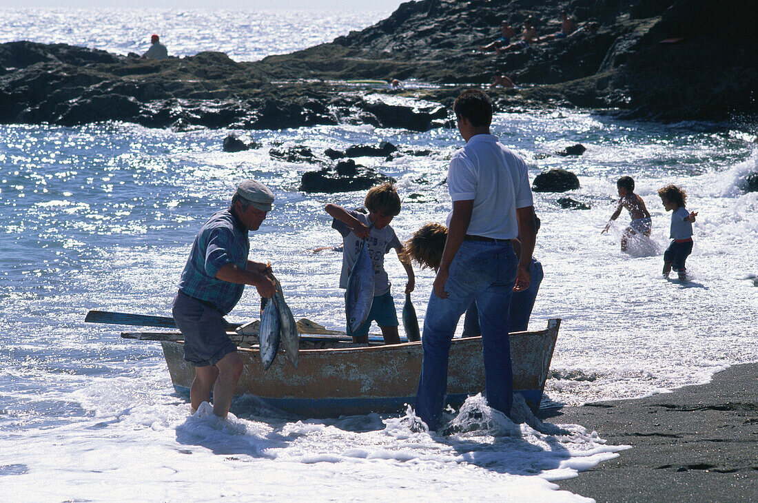 Fischerfamilie landet ihren Fang in der Brandung des schwarzen Strandes von Ajuy an, Fuerteventura, Kanarische Inseln, Spanien