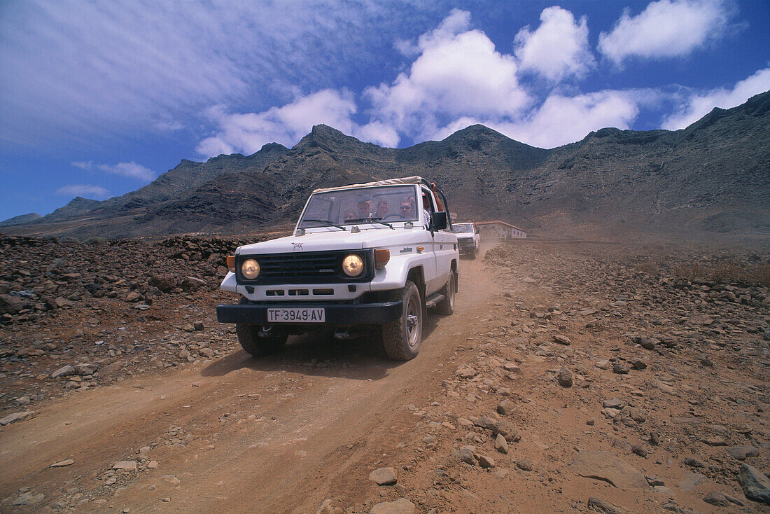 People driving two off-road vehicles in the desert mountains above Playa de Barlovento, Jandía Peninsula, Fuerteventura, Canary Islands, Spain