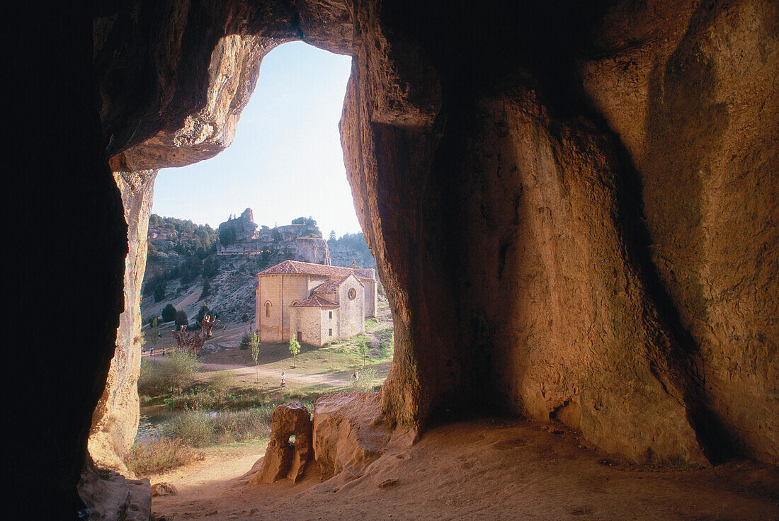 Blick aus dem Eingangsloch einer Felsenhöhle auf die Kapelle der Ermita de San Bartolomé, Provinz Soria, Altkastilien, Castilla-León, Spanien