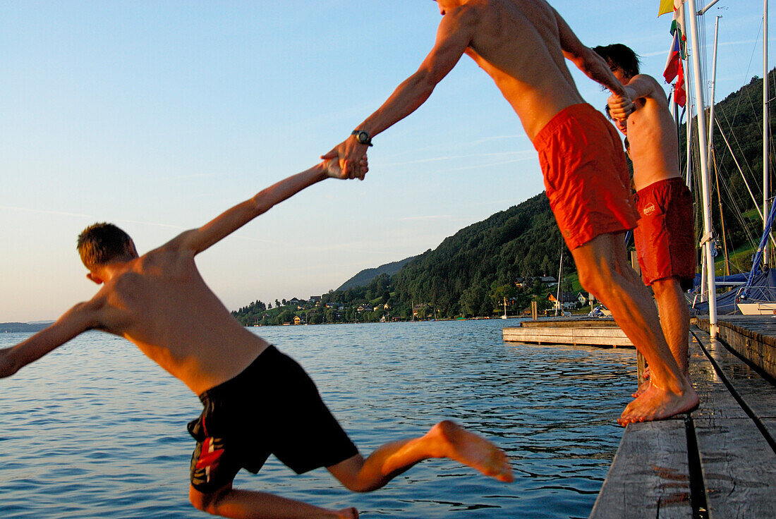 Junge Männer springen vom Bootssteg, Attersee, Salzkammergut, Salzburg, Österreich