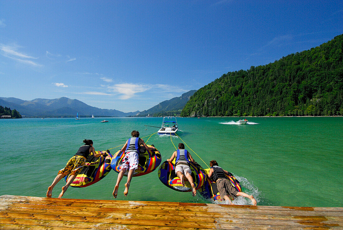 Vier junge Leute beim Tube Riding auf Abersee (Wolfgangsee), Salzkammergut, Salzburg, Österreich