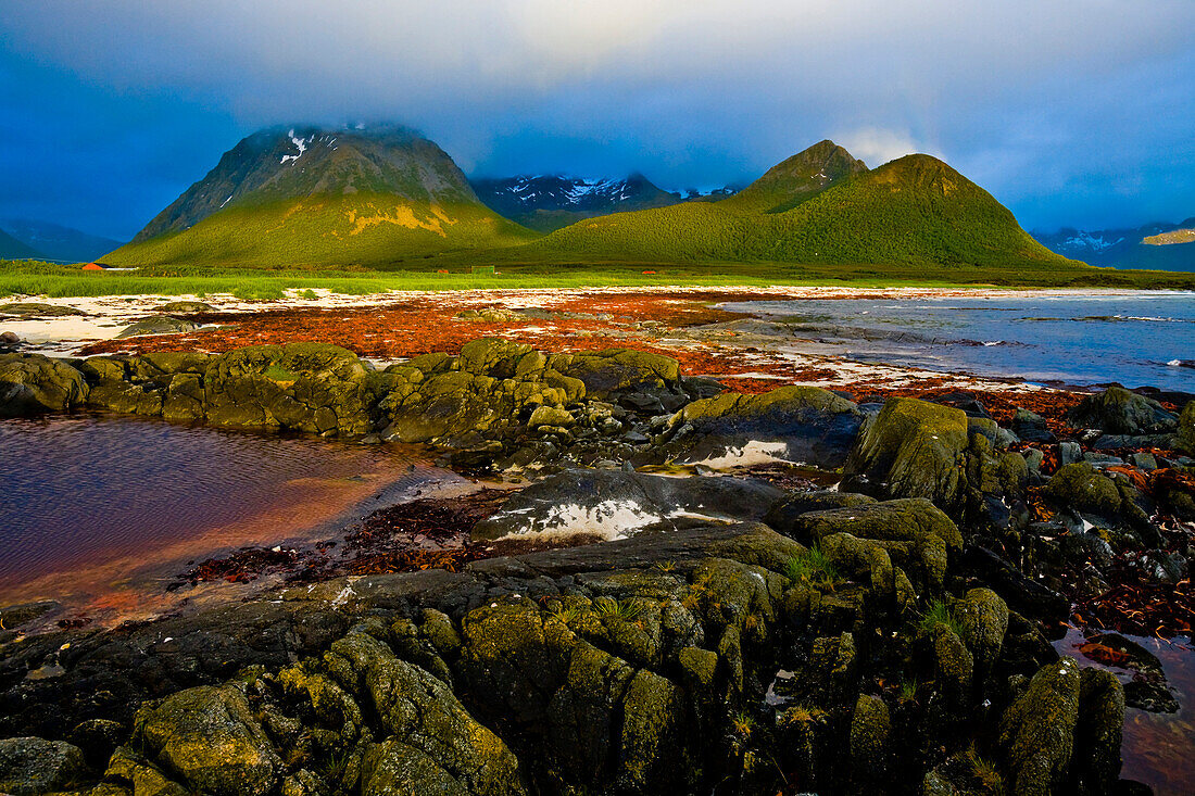 Mitternachtsonne und Wolken verhangene Berge am Strand von Hadselsand, Insel Austvagoya, Lofoten, Norwegen.