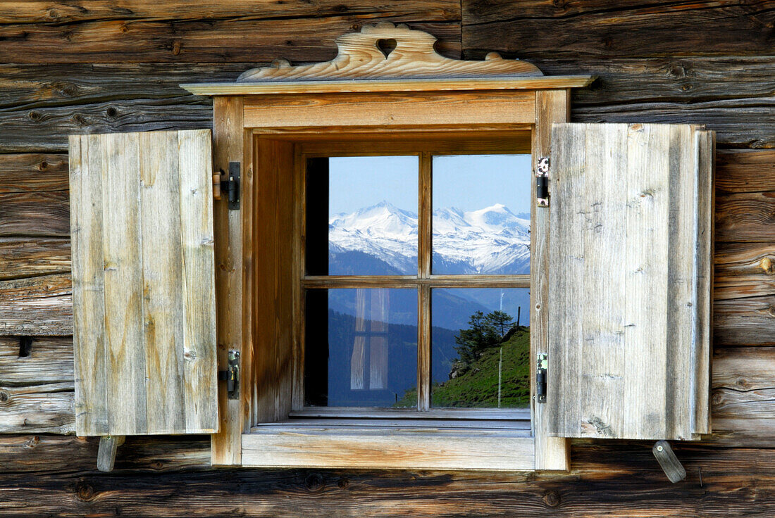 Reflection of snow covered mountains in alpine hut window, Wilder Kaiser range, Kaiser range, Tyrol, Austria