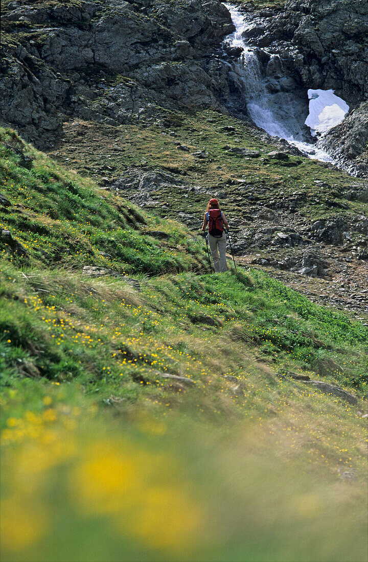 Hiker in Valle delle Mine, waterfall in background, Livigno, Lombardy, Italy