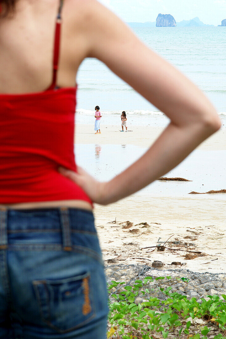 Female tourist watching  two little girls at the beach, Krabi, Thailand; Asia