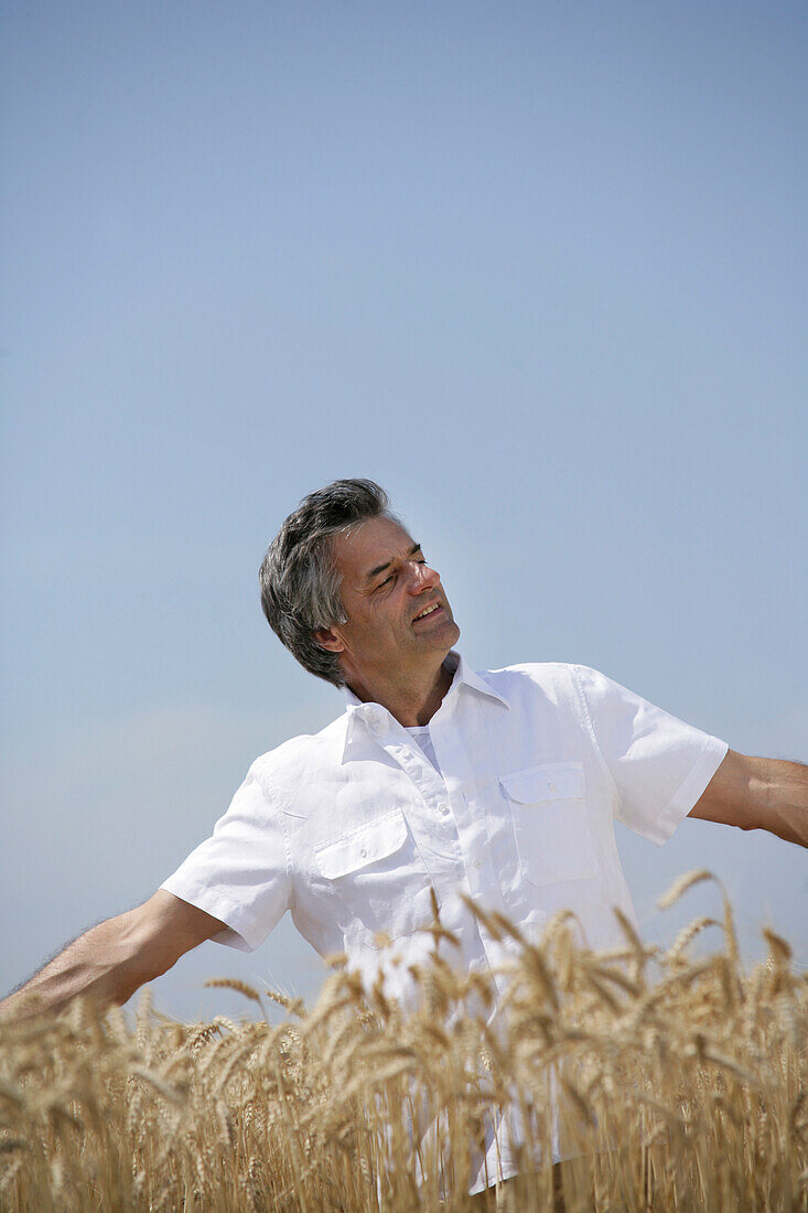 Man with outstreched arms standing in a corn field, Carinthia, Austria