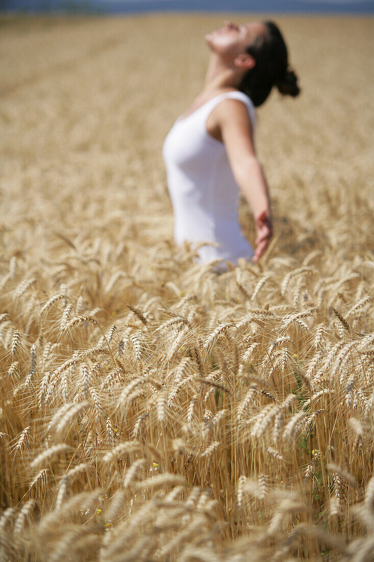 Frau mittleren Alters meditiert in einem Getreidefeld