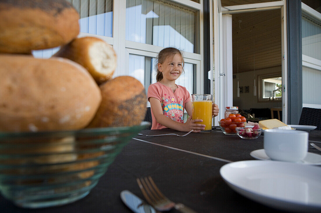 Junges Mädchen deckt Frühstückstisch auf Terrasse von Ferienhaus, Henne Strand, Jütland, Dänemark, Europa