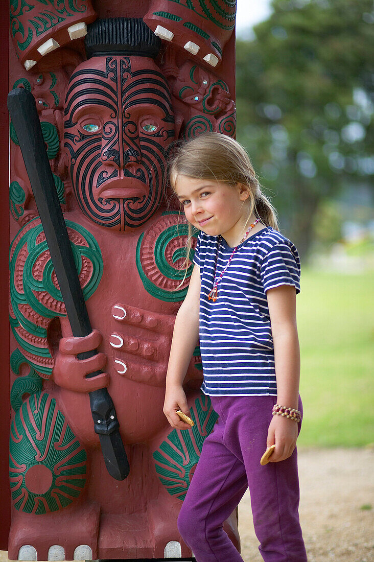 Mädchen an Maori Schnitzerei im Waitangi Museum, Teil eines Hauses der Maori, Bay of Islands, Northland, Nordinsel, Neuseeland