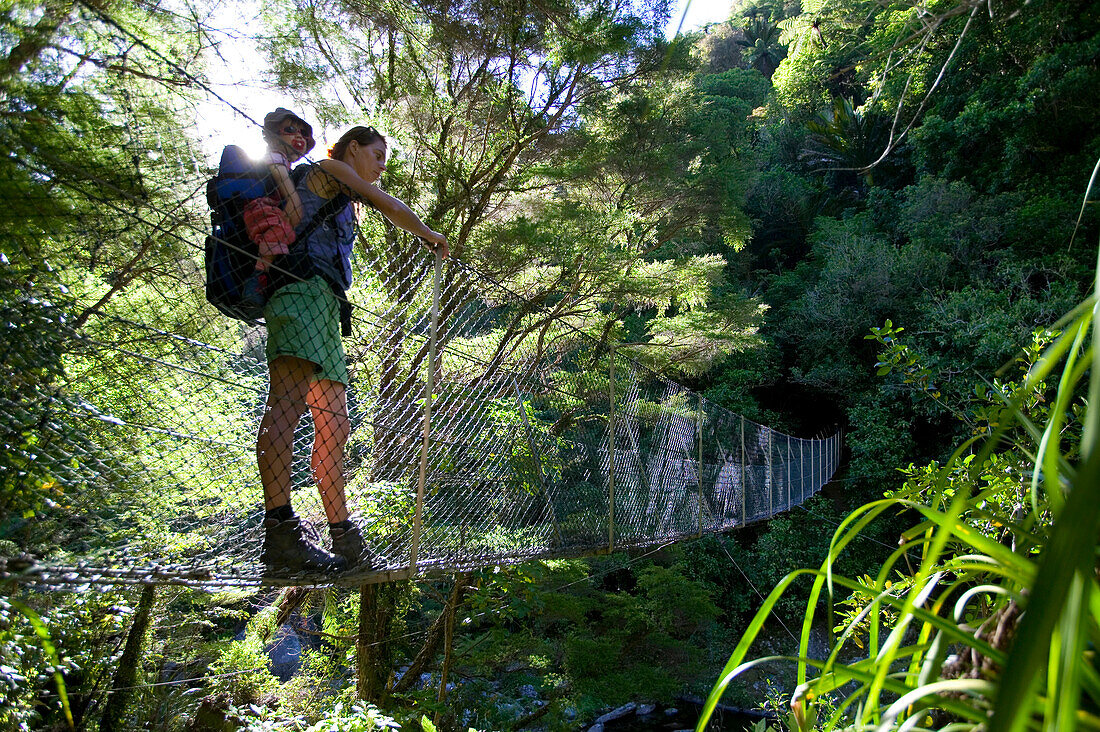 Mutter mit Kind auf Hängebrücke über Fluß, Wanderung im Abel Tasman Nat.Park, Nordüste, Südinsel, Neuseeland