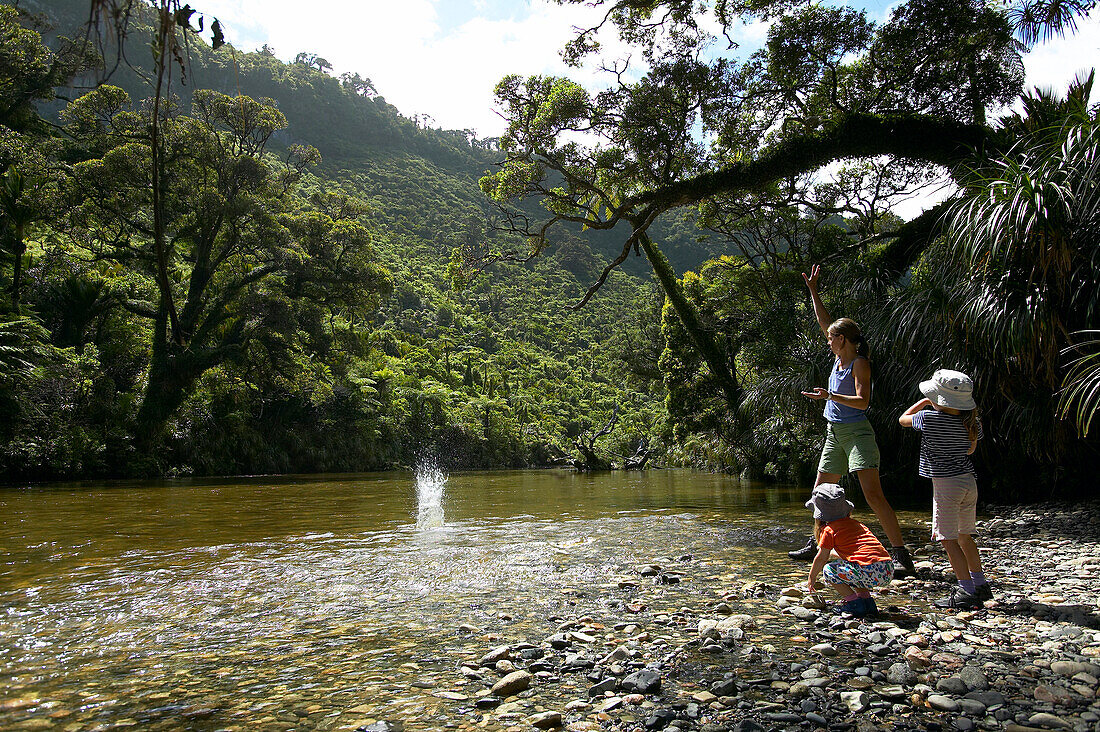 Mother with children at riverside, hiking inPunakaiki National Park, north of Hokitika, Westcoast, South Island, New Zealand