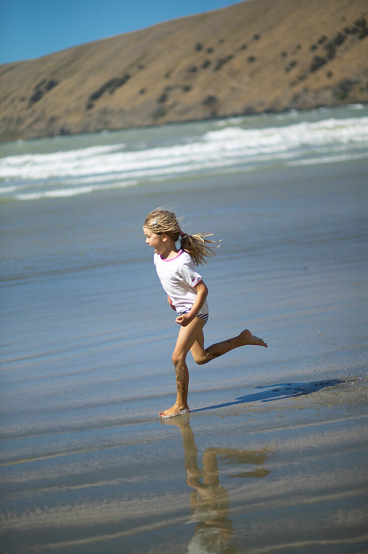 Girl running at the beach of Little Okains Bay at low tide, Okains Bay, Bank`s Peninsula, east coast, South Island, New Zealand