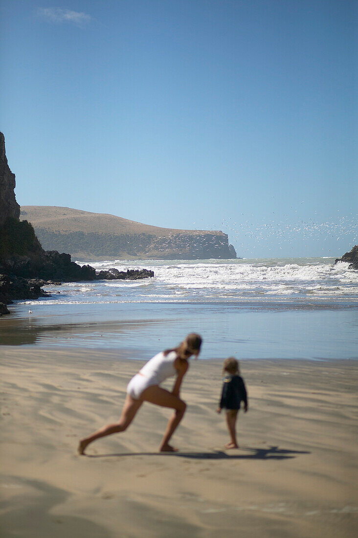 Mutter und Kind spielen am Strand der Little Okains Bay, flaches Wasser, Bank's Peninsula, Ostküste, Südinsel, Neuseeland