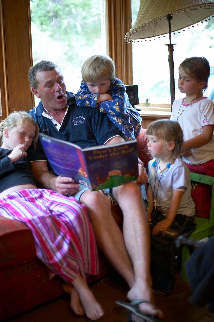 Father reading stories to children ,Rowendale Homestead Farm, B & B, Okains Bay Bank`s Peninsula, east coast, South Island, New Zealand