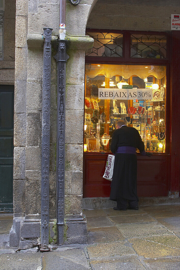 Rainwater pipe with priest looking in a shop window in the background, Santiago de Compostela, Galicia, Spain